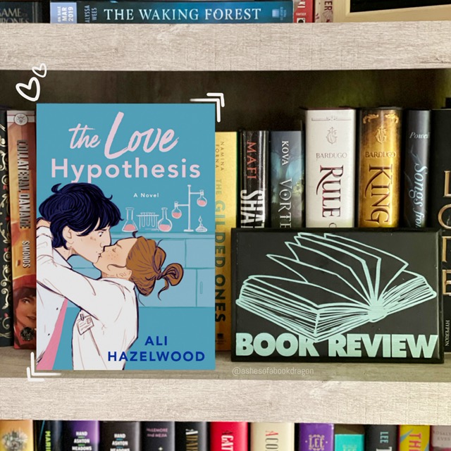 A book labeled 'The Love Hypothesis' depicting a short woman with brown hair, in a lab coat, kissing a taller man. The man is surprised and has black hair. A science lab is show in the background. 